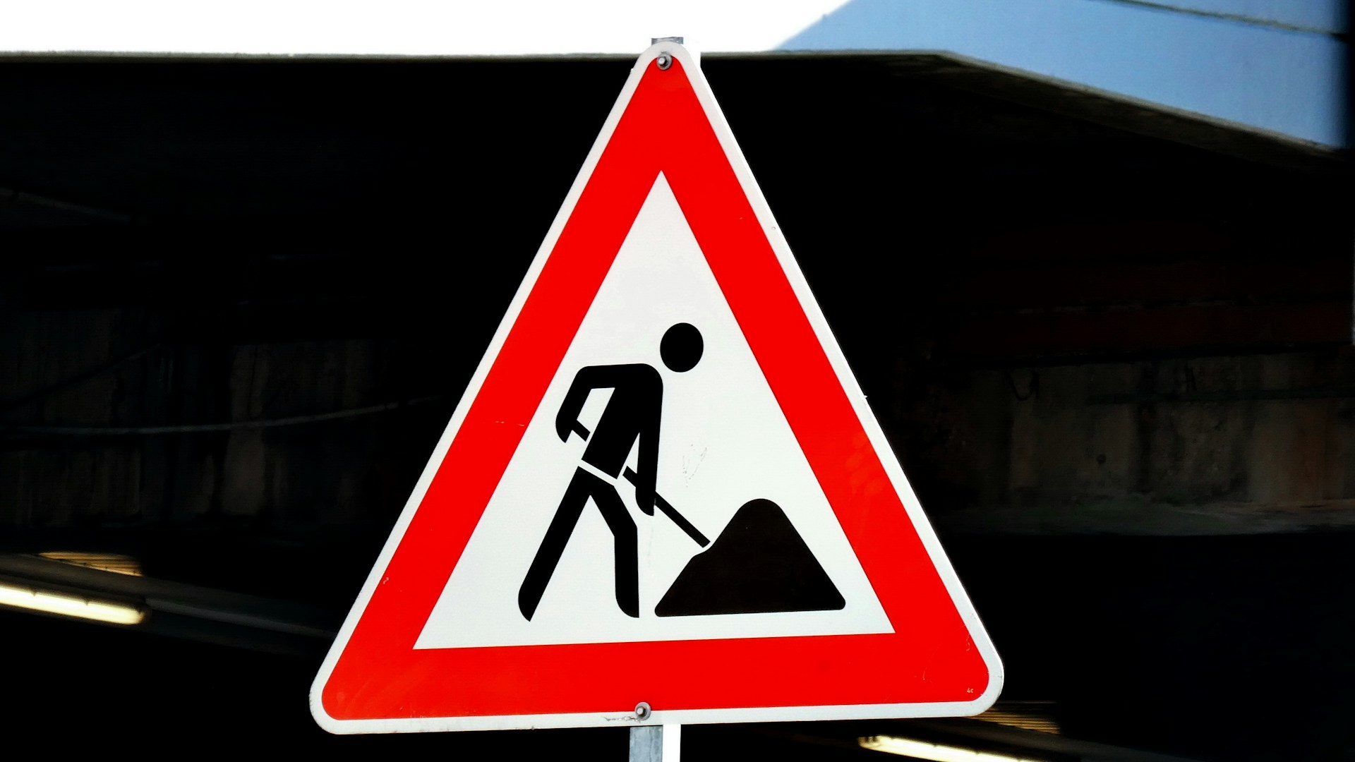 A roadwork warning sign features a person digging with a shovel.