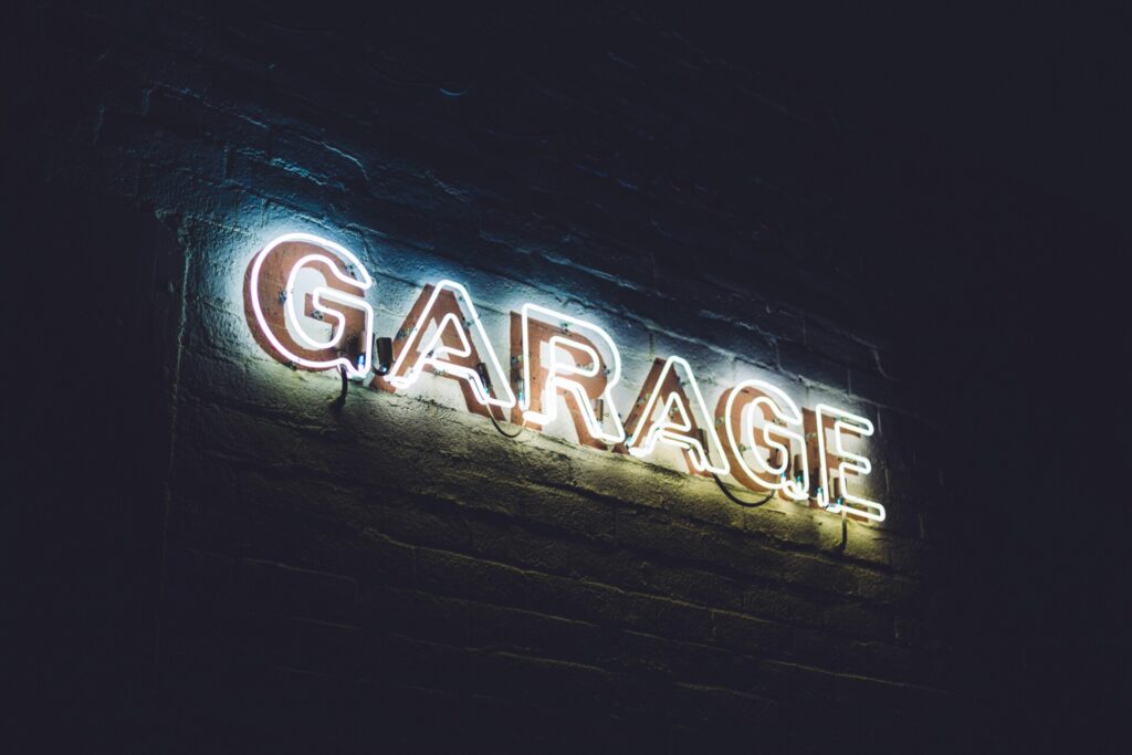 Neon sign reading “GARAGE” glows against a dark brick wall.