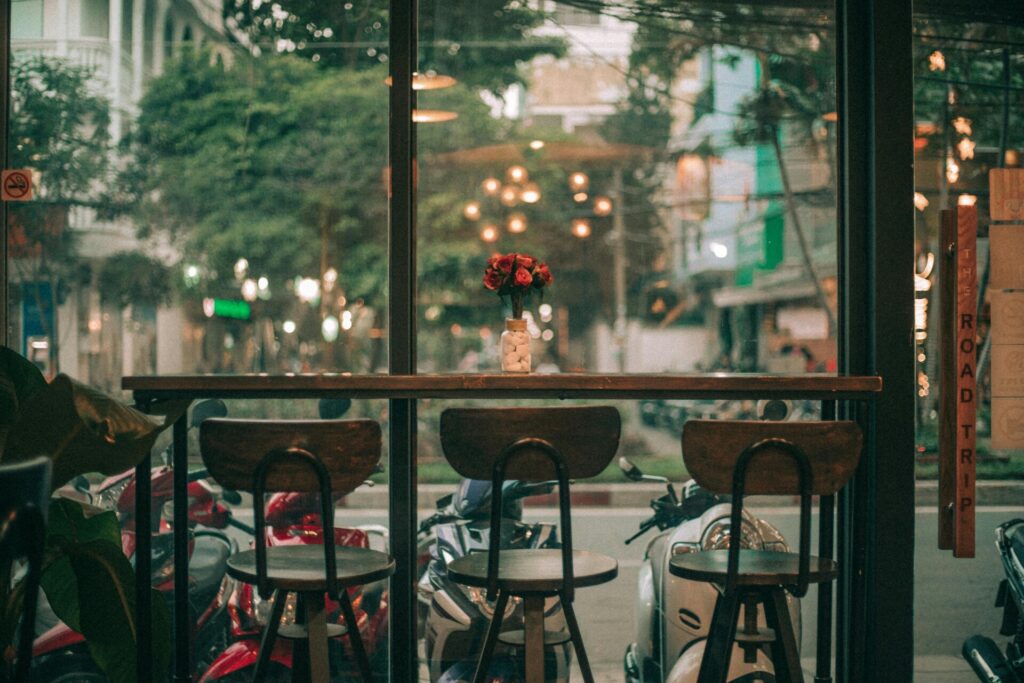A cozy cafe interior with a window view of a street and parked scooters.