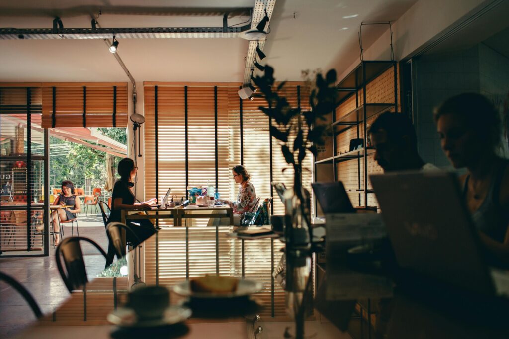 People working on laptops in a cozy cafe with warm lighting.
