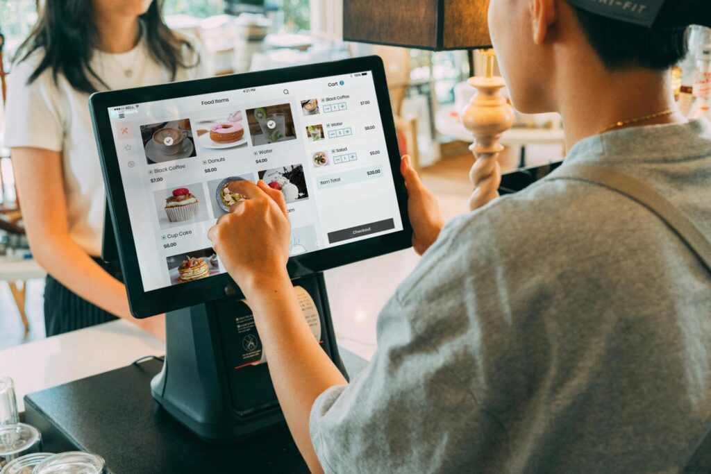 A person interacts with a digital ordering system in a café setting.