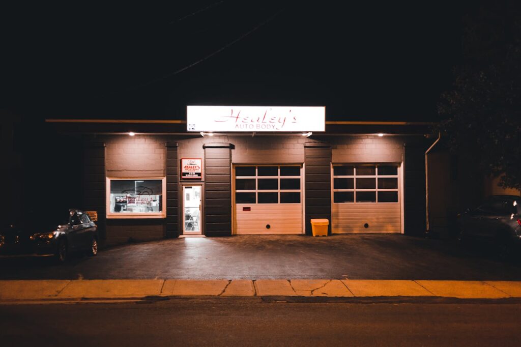 A brightly lit auto body shop at night with a visible sign.