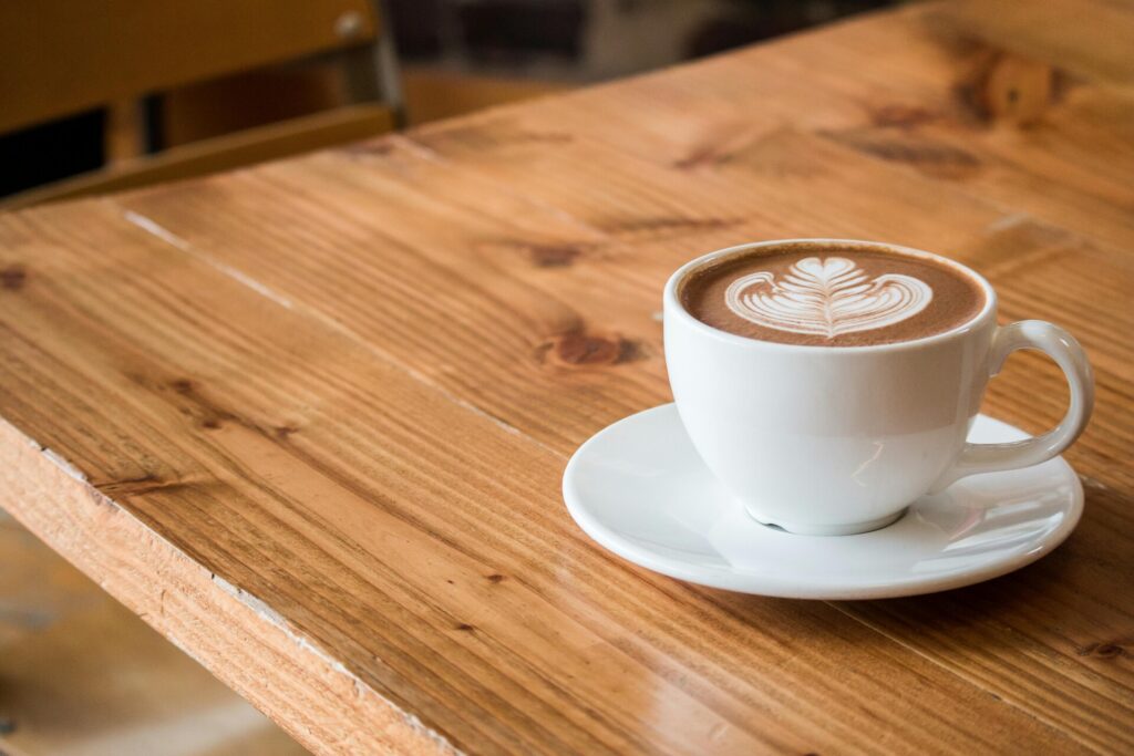 A cappuccino with latte art on a wooden table in a café.