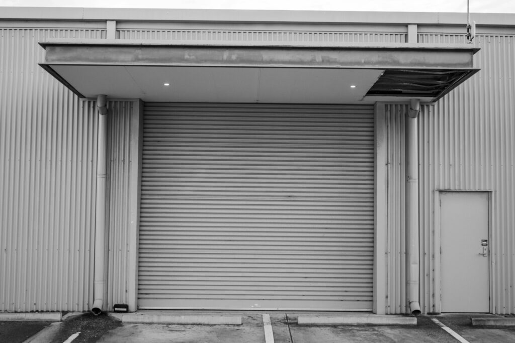 Industrial building with a large closed metal roller door in monochrome.