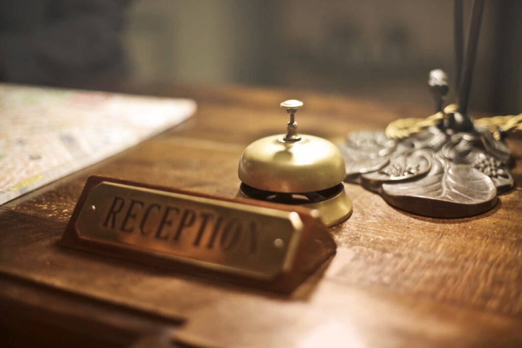 A brass reception bell on a wooden counter with a sign reading "RECEPTION."