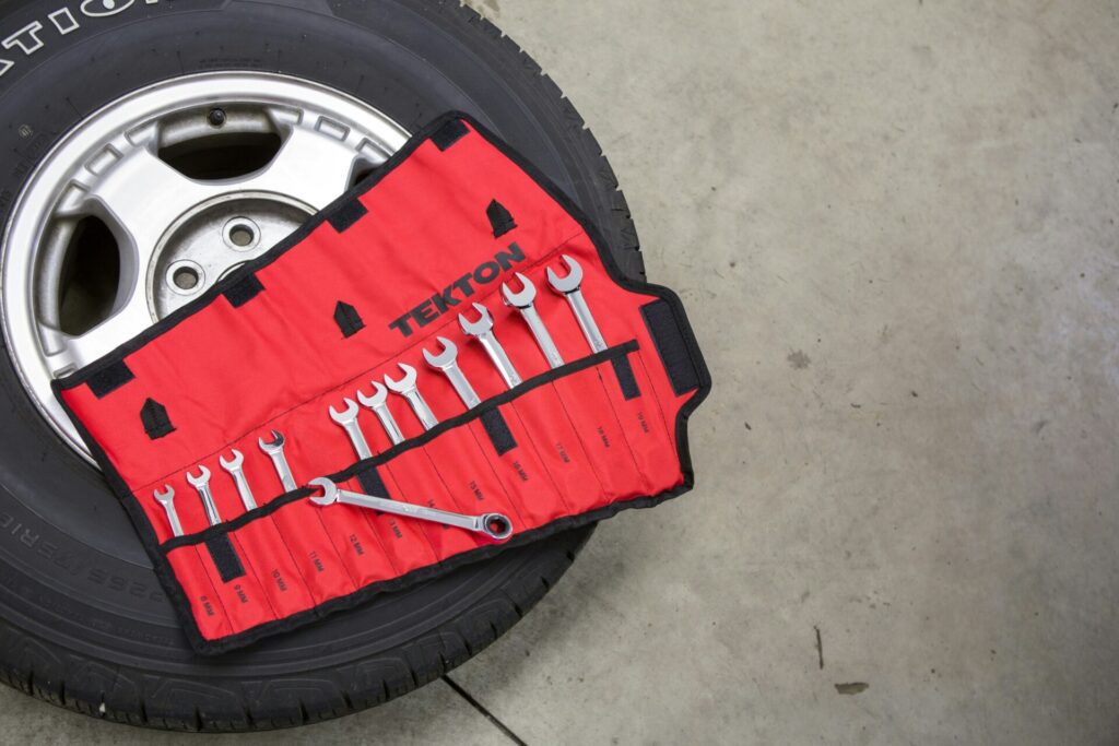 A red wrench set is displayed on a tire in a garage setting.