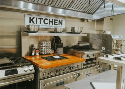 Modern commercial kitchen with stainless steel appliances and a wooden countertop.