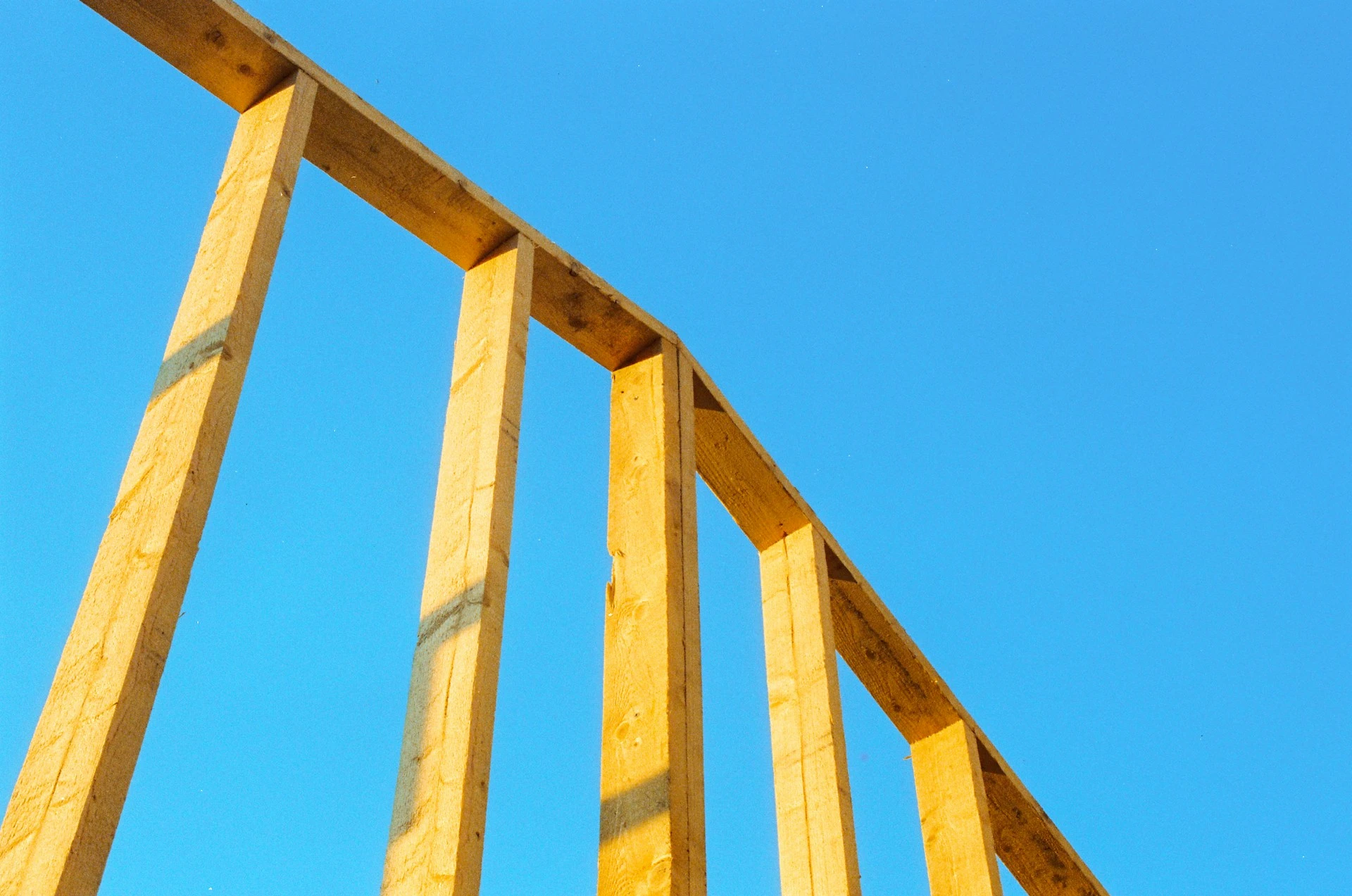 Wooden beams form a structure against a clear blue sky.