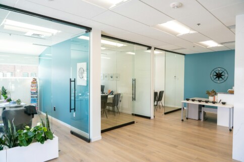 Modern office space with glass walls and blue accent wall.