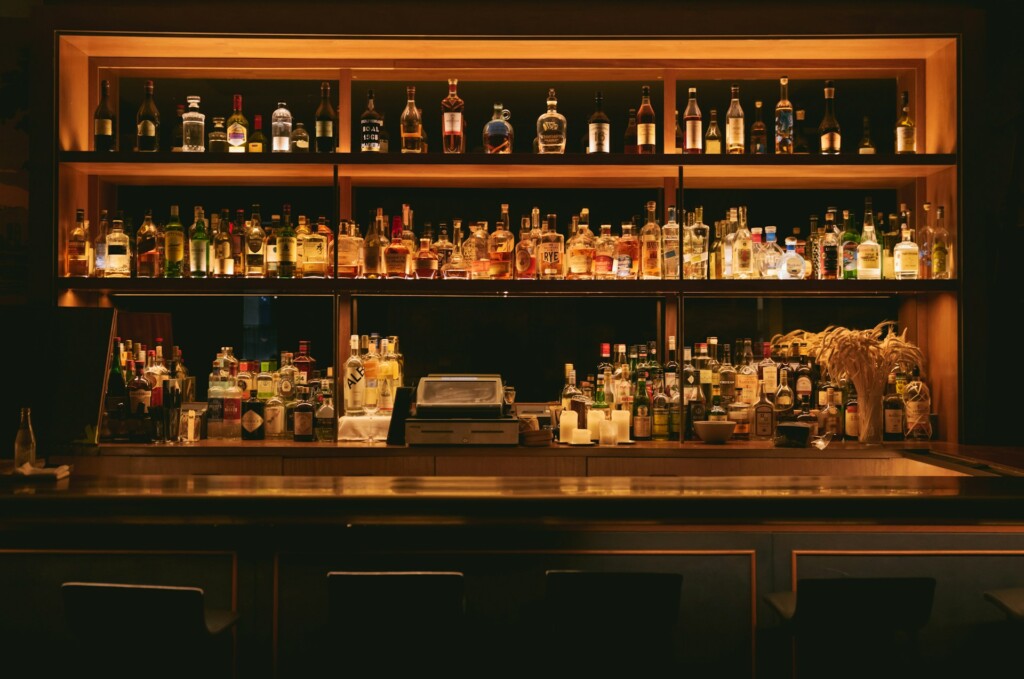 Dimly lit bar with numerous bottles of liquor on display shelves.