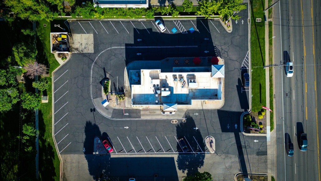 Aerial view of a large parking lot with few cars and a central building.