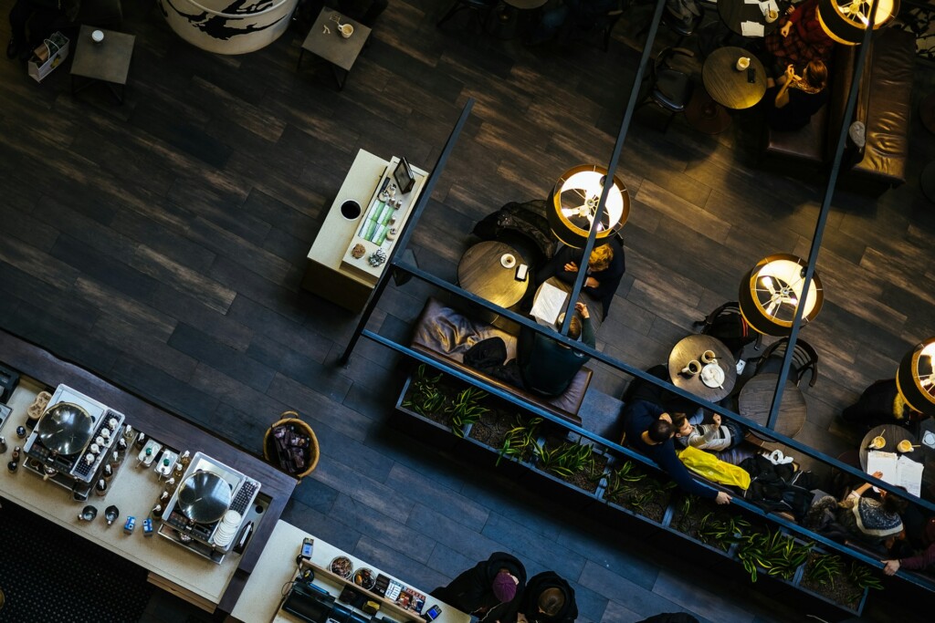 Overhead view of a busy café with people sitting at tables and soft lighting.