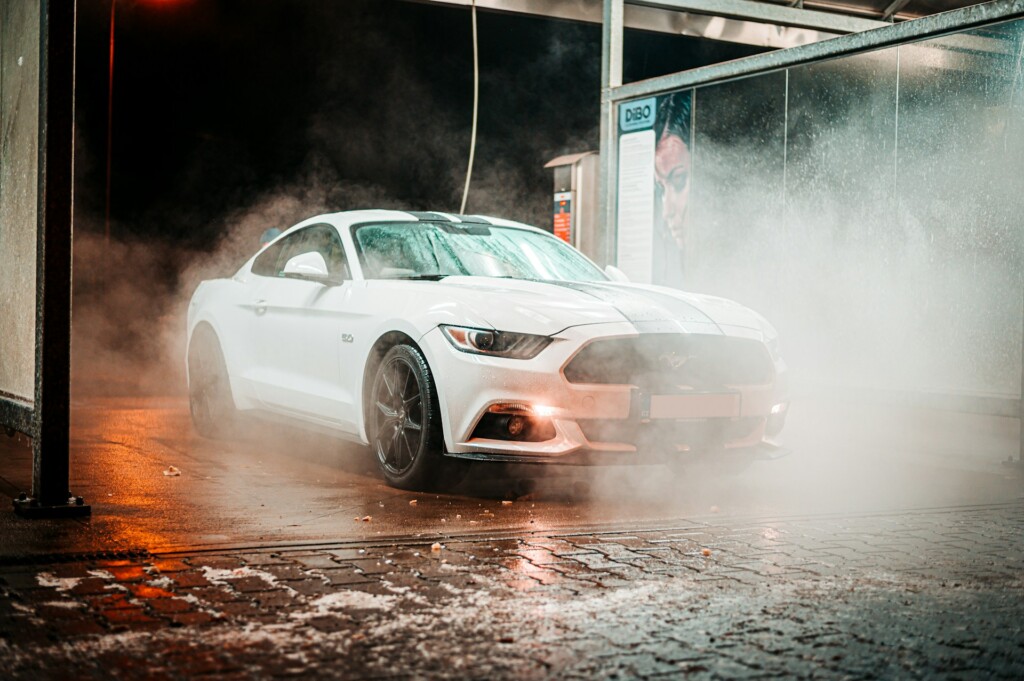 White sports car being washed in a dimly lit car wash.
