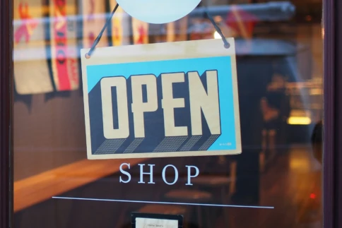 A bright open sign hangs on a shop window, inviting customers inside.