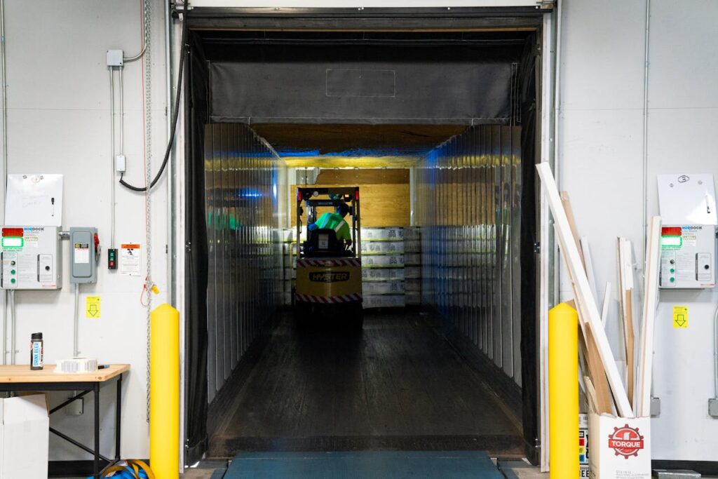 A forklift loads pallets into a trailer at a loading dock.