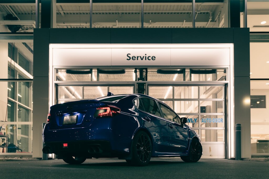 Blue car parked outside a service station at night.