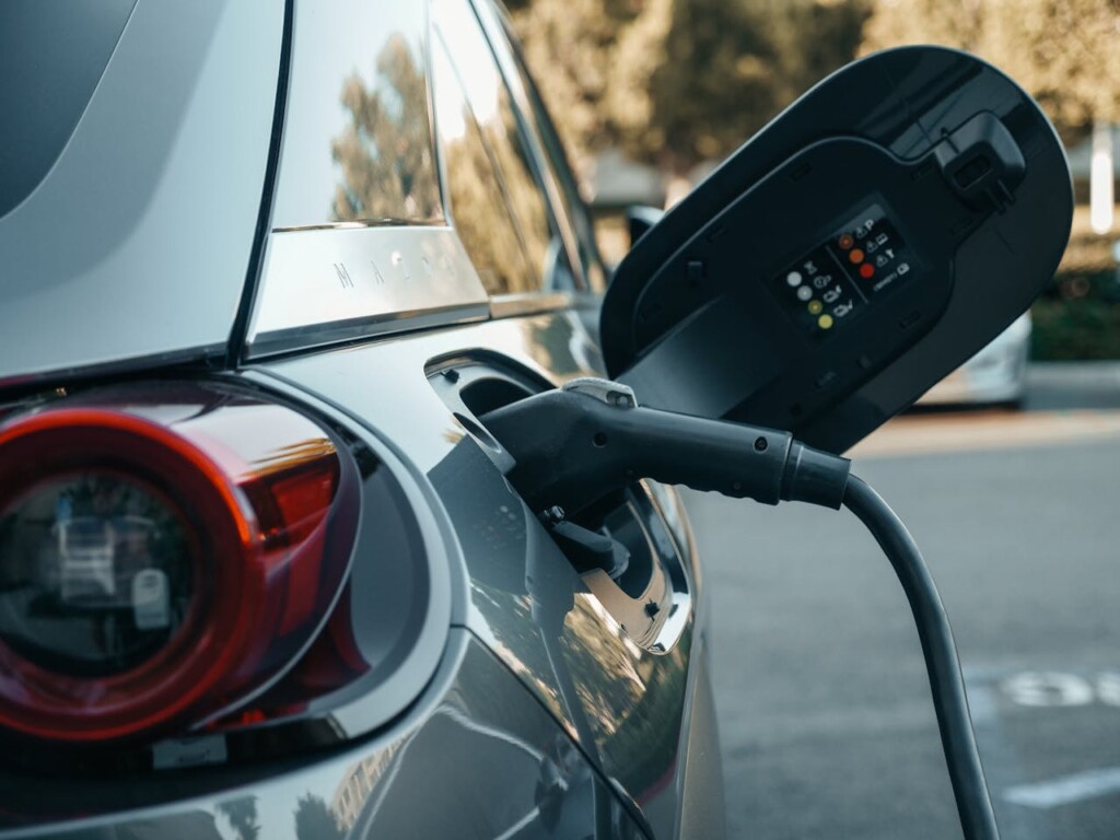 An electric car charging at a public charging station in a parking lot.