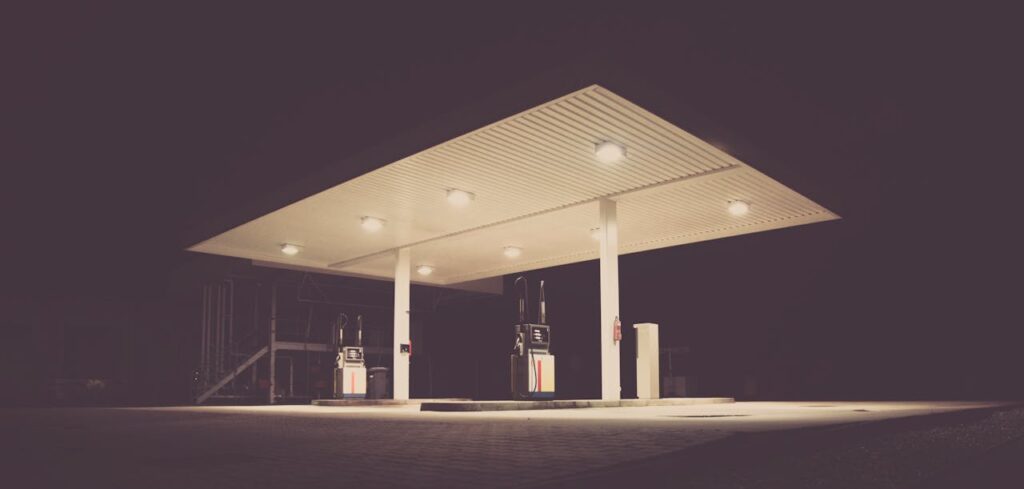 A quiet, empty gas station is illuminated at night against a dark sky.