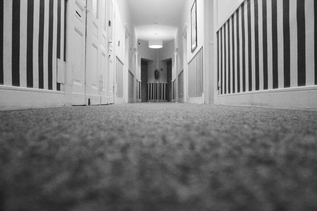 Black and white photo of a long, patterned hallway with doors.