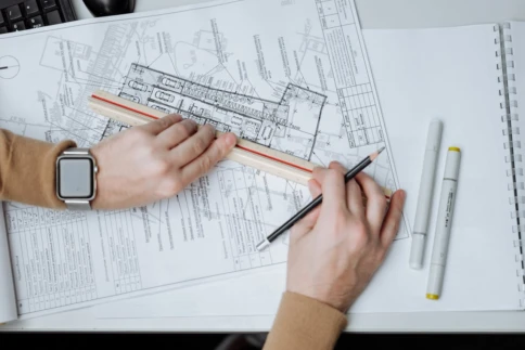 Person uses a ruler and pencil to work on architectural blueprints.