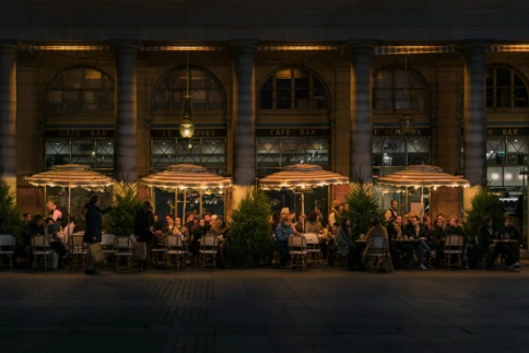 People dining at a warmly lit outdoor café during the evening.