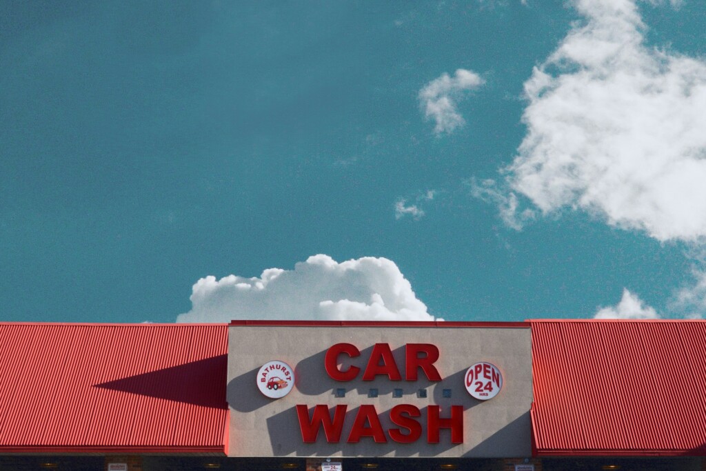 A car wash building with a bright red roof under a blue sky.