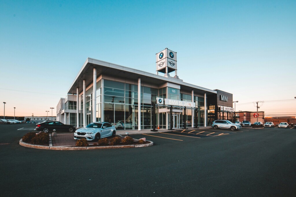 A BMW car dealership with multiple cars parked outside at sunset.