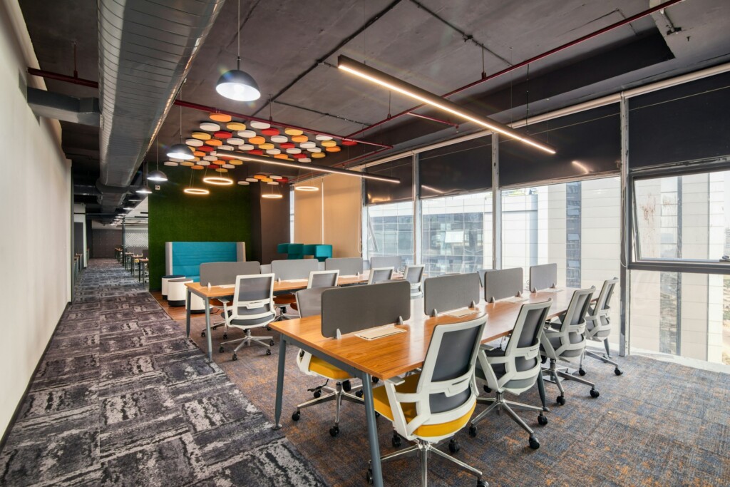 Modern office space with desks, swivel chairs, and colorful ceiling decor.
