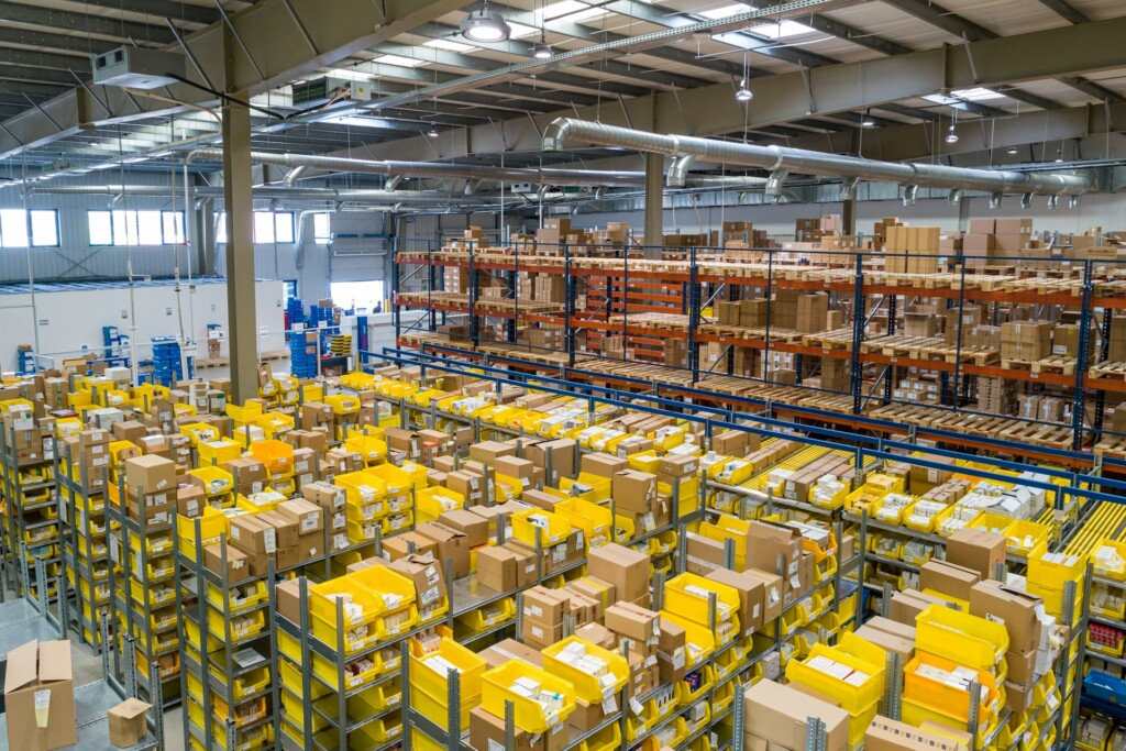 A large warehouse filled with shelves of boxes and yellow containers.