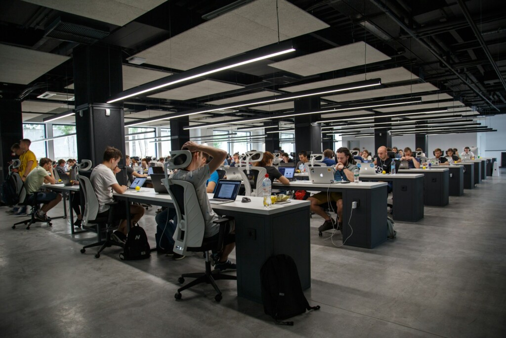 A large, modern office space with rows of people working on laptops.