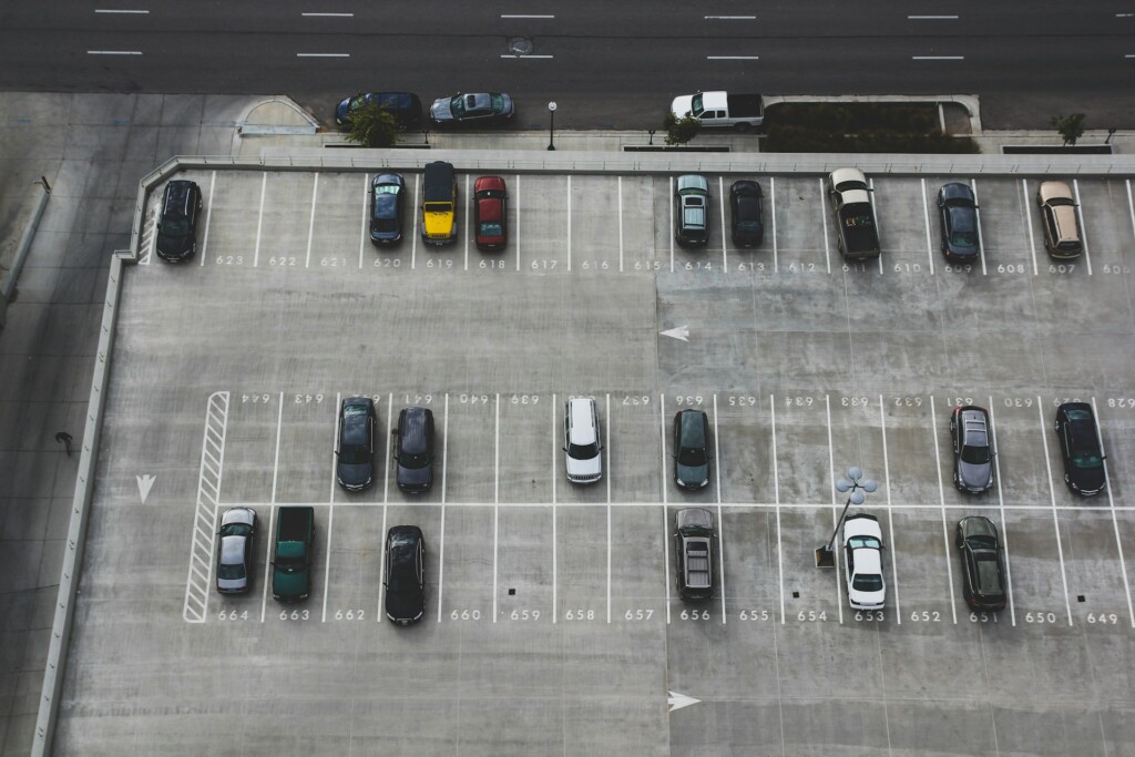Aerial view of a spacious and partly-filled urban parking lot with vehicles.
