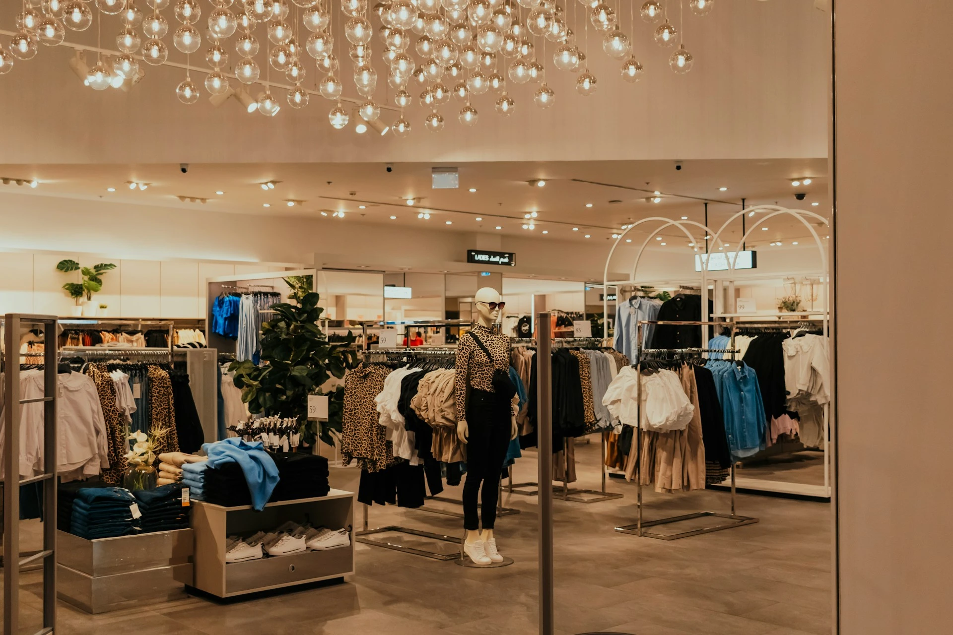 Modern clothing store interior with mannequins and neatly arranged apparel displays.
