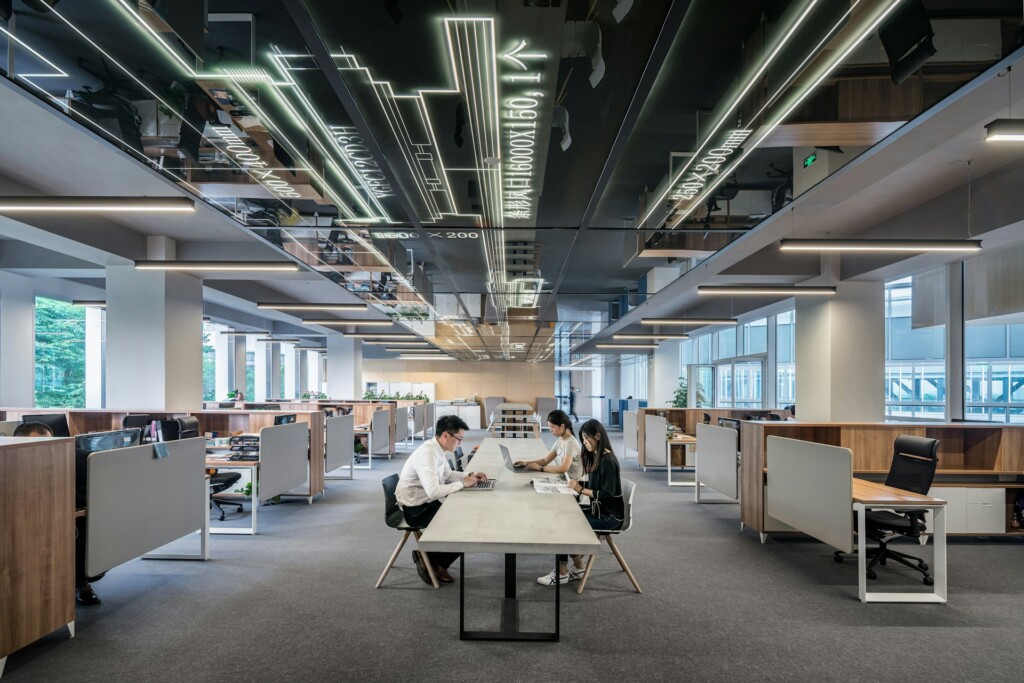 Modern open-plan office with employees working at desks under sleek design.
