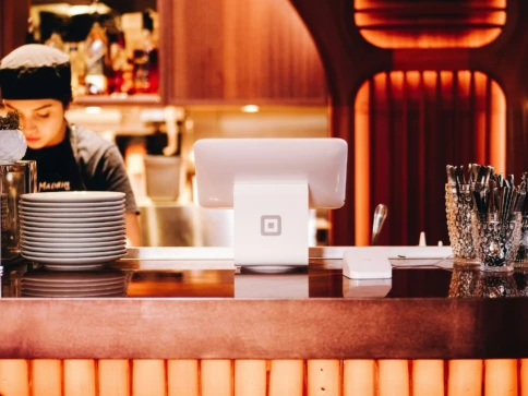 A restaurant counter with a point-of-sale system and stacked plates.