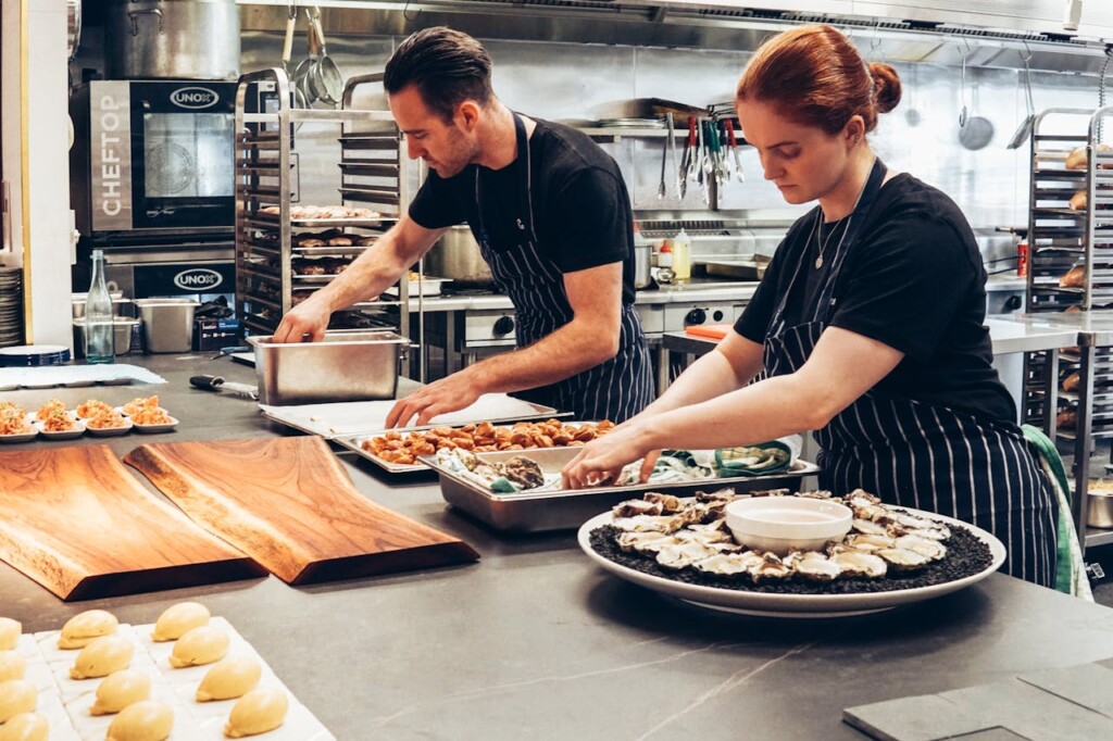 Two chefs preparing gourmet dishes in a professional kitchen setting.