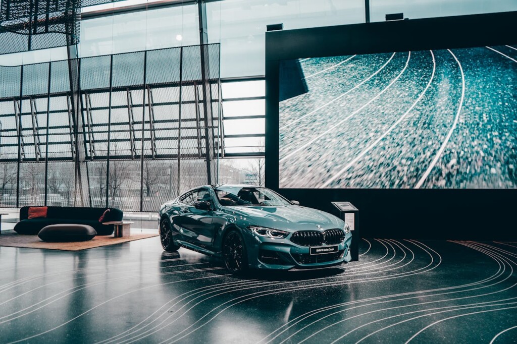 A sleek blue car is displayed in a modern showroom with large windows.