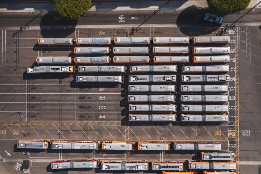 Aerial view of several buses parked in a large, organized lot.
