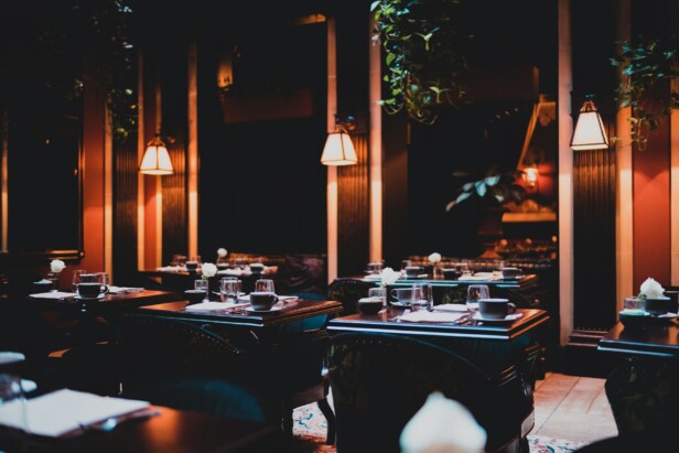 A dimly lit restaurant with elegant dark wood tables and ambient lighting.