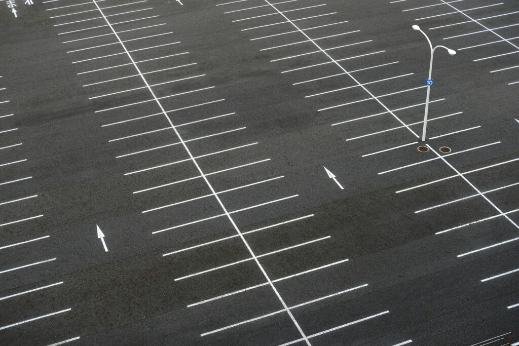 An empty parking lot with white lines and directional arrows on asphalt.