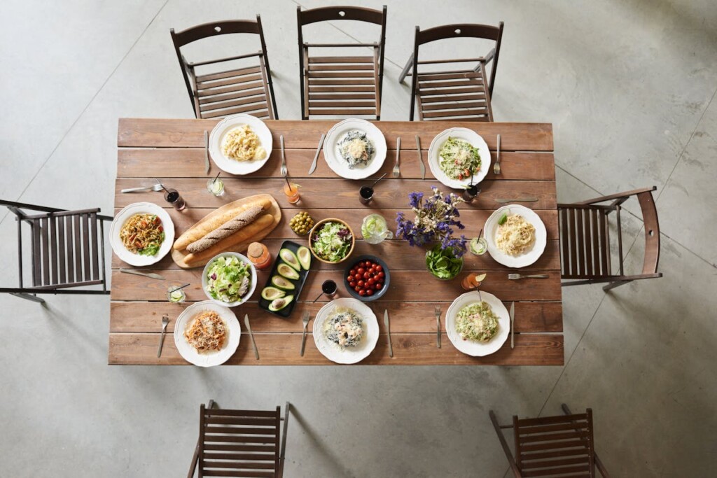 Top view of a dining table set with pasta dishes and salads.
