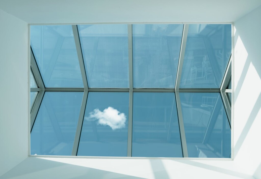 A lone cloud is visible through a large glass-paneled ceiling.