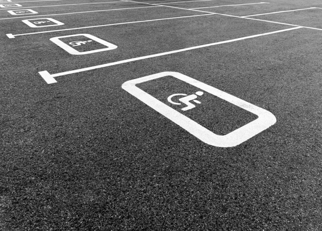 Black and white image of parking spaces with a handicap symbol.