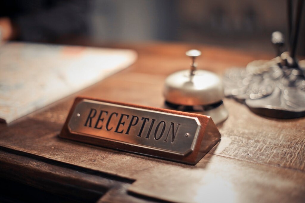 A wooden reception desk with a bell and reception sign.
