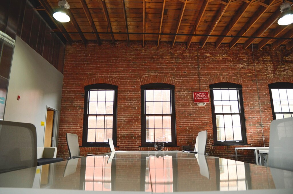 Spacious industrial-style office with brick walls and several windows.