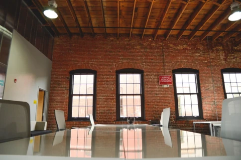 Spacious industrial-style office with brick walls and several windows.